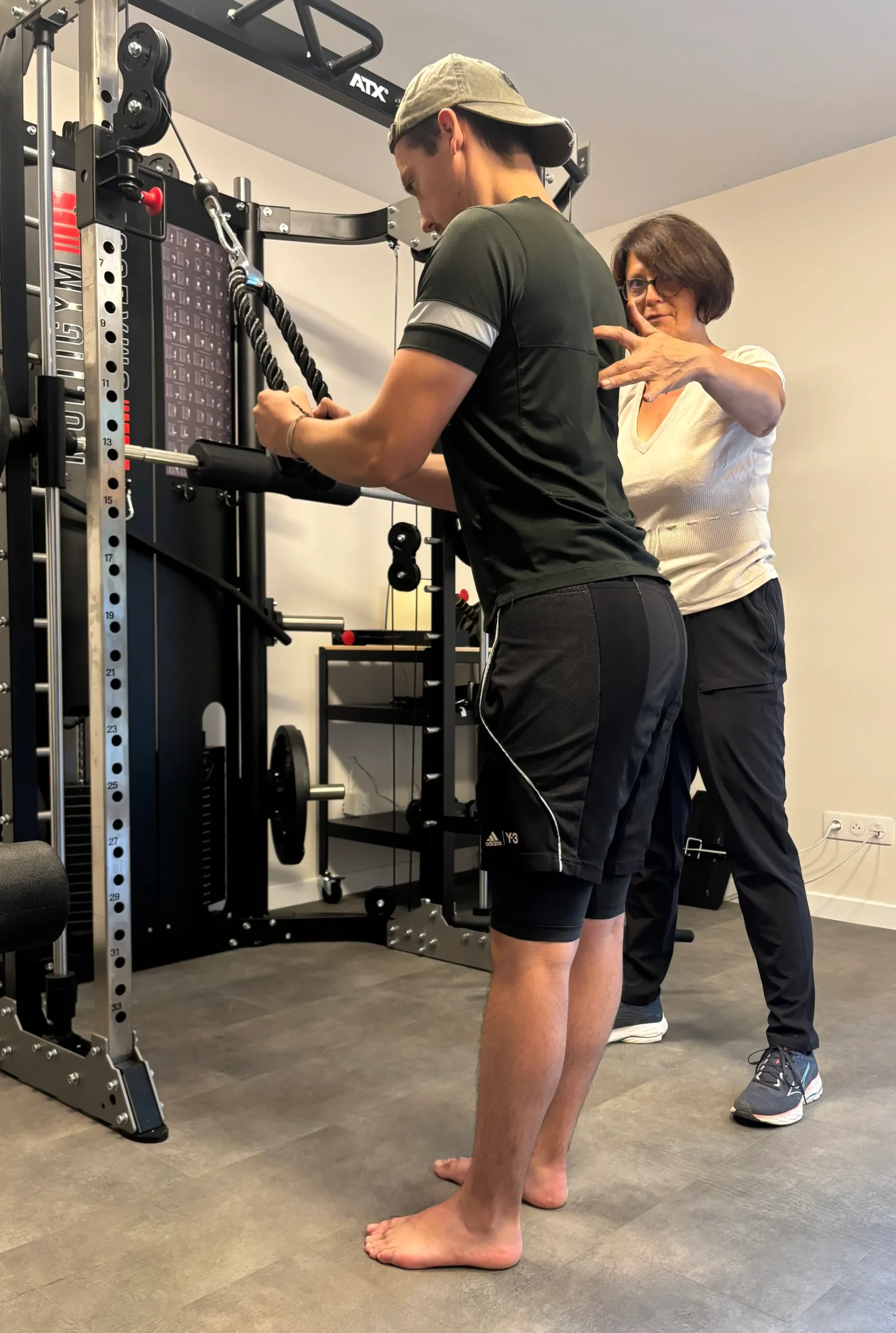 Correction de posture par la coach pendant un exercice de triceps à la corde sur poulie haute